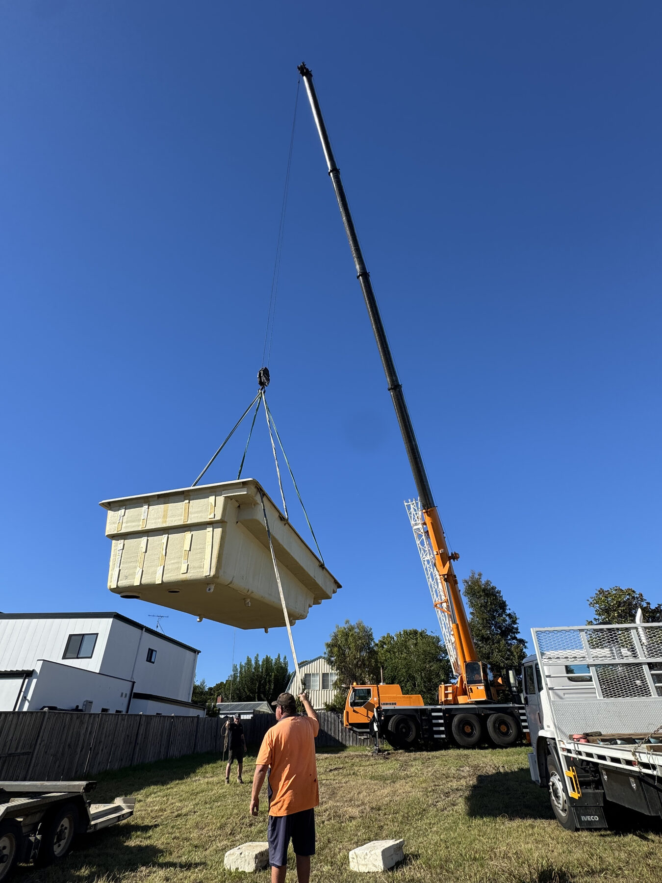 Crane lifting a precast pool shell into place