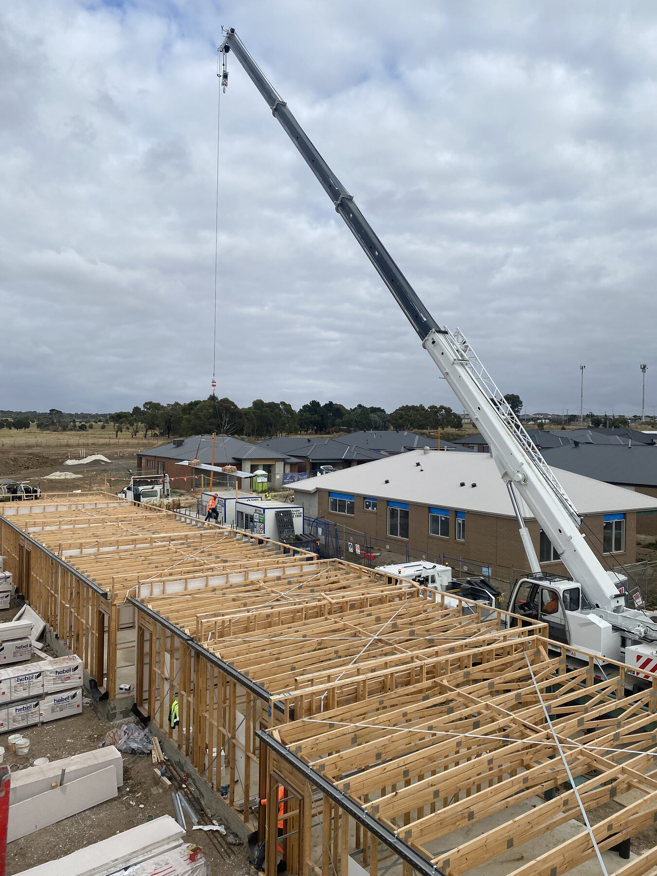 Slew crane placing roof trusses on a new home